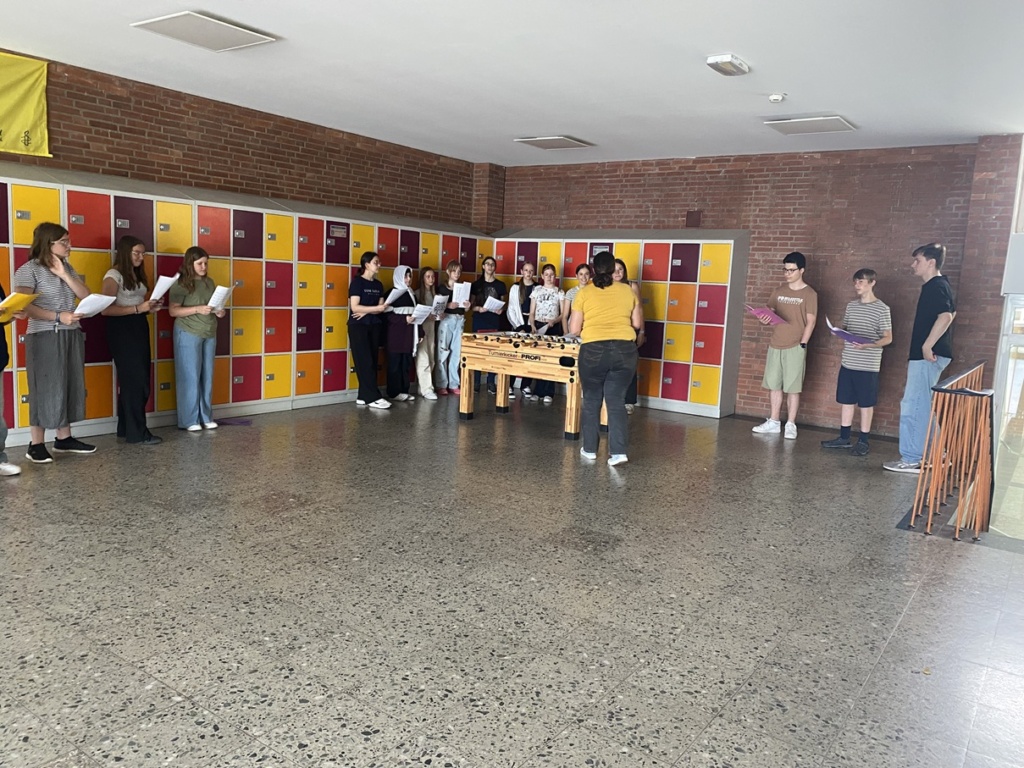 Chor1 In der Pausenhalle stehen Schülerinnen und Schüler und singen.