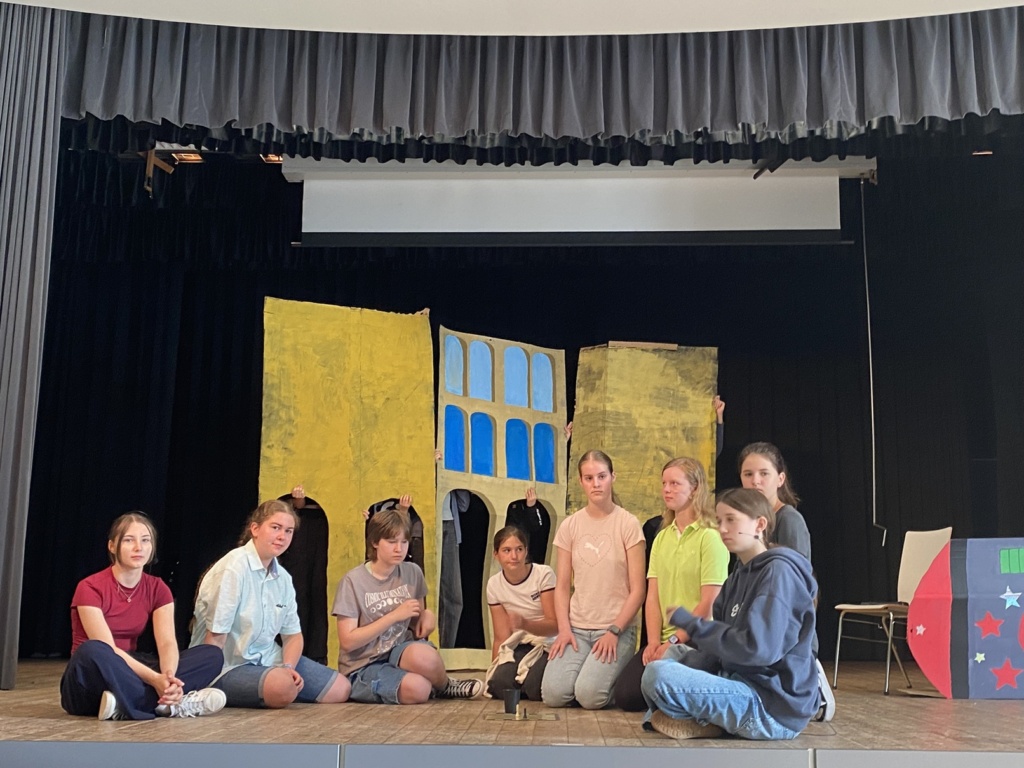 Das fliegende Klassenzimmer 8 Schülerinnen und Schüler spielen "Das fliegende Klassenzimmer" auf einer Bühne mit Hauskulissen.