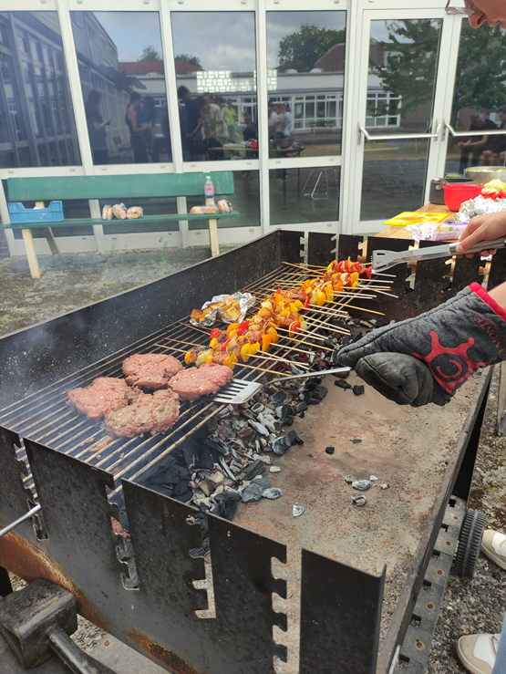 Kulinarik2 Auf einem Grill werden Fleischstücke und Gemüsespieße zubereitet.