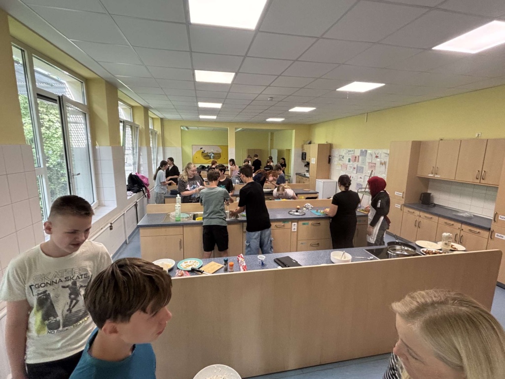 Multikulturelles Kochbuch1 Blick in die Schulküche mit arbeitenden Schülerinnen und Schülern.