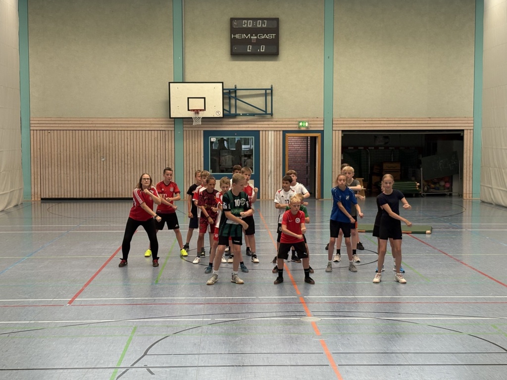 Sport_Haka Schülerinnen und Schüler tanzen in einer Sporthalle mit Baskettballkorb den Haka, den Tanz Neufundlands.