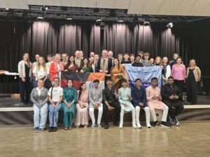 Gruppenbild aller indischen Schülerinnen und Schüler mit ihren Lehrkräften und deutschen Gastschülern auf einer schwarzen Bühne.