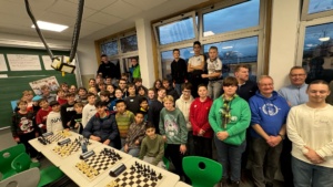 IMG-20251202-WA0022 Alle Schachturnierteilnehmenden und die beteiligten Lehrkräfte sind in einem Schulraum mit Schachbrettern zu sehen.