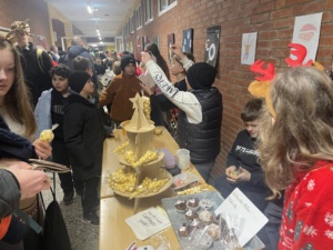 IMG_7390 Gutgelaunte Schülerinnen und Schüler verkaufen weihnachtliche Produkte, Publikum flaniert im langen Gang.