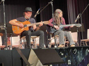 IMG_7398 Zwei Menschen spielen Konzertgitarre auf einer Bühne.