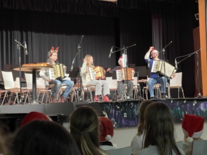 IMG_7401 Vier Lernende mit Weihnachtsmützen spielen Akkordeon.